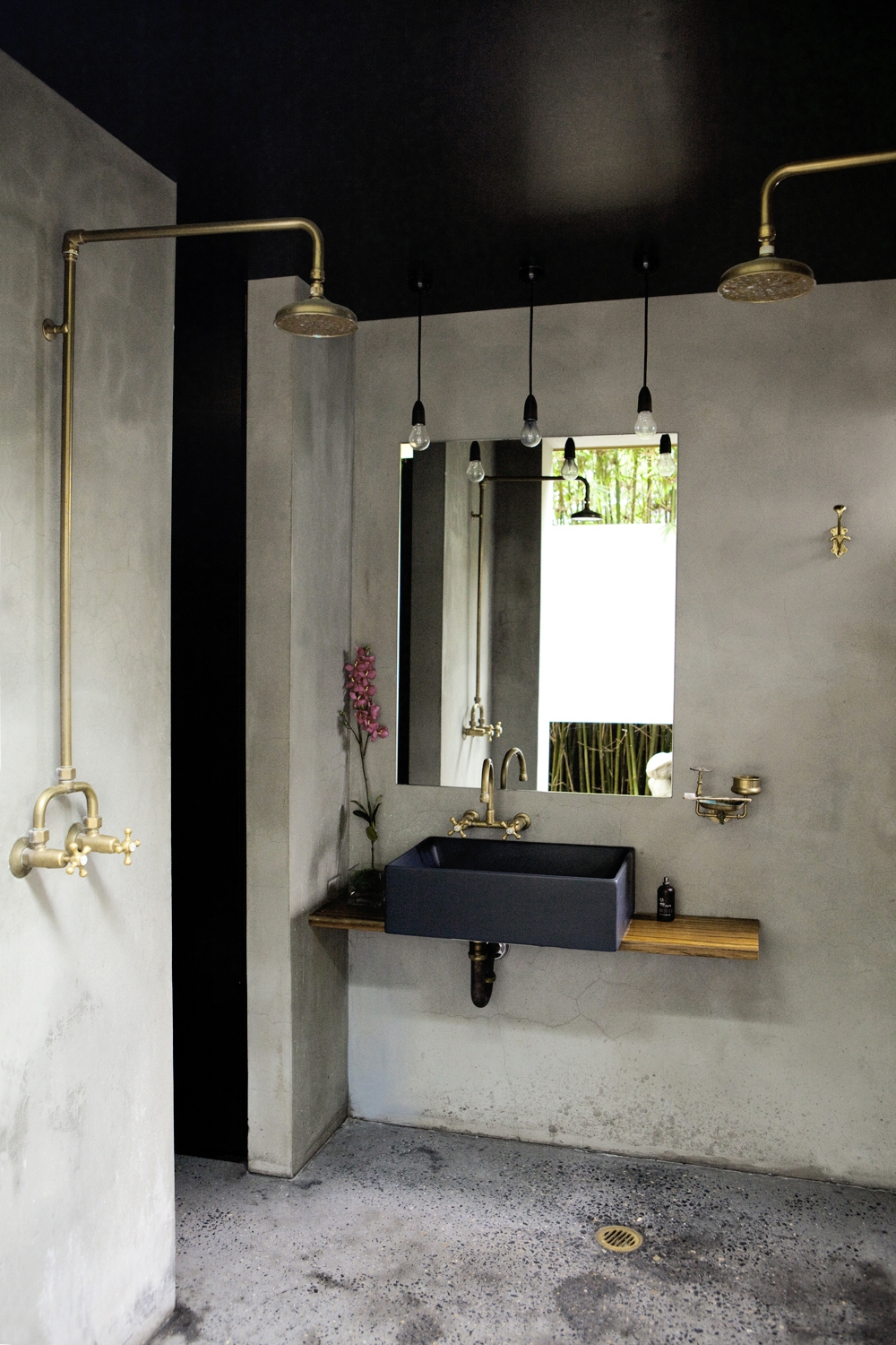 Industrial bathroom with concrete walls and copper shower fixtures