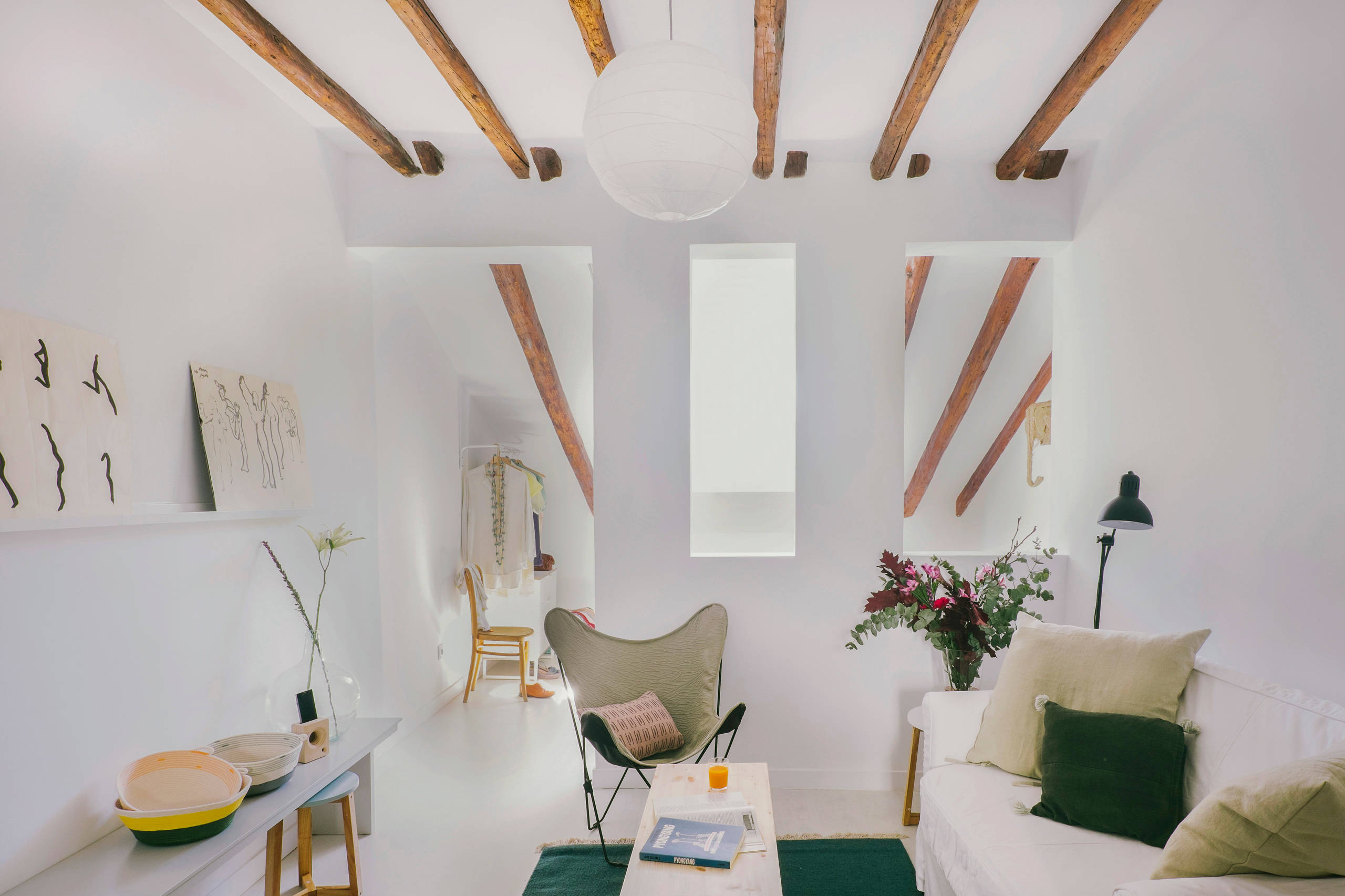 Minimalist bohemian living room with cut-out walls and wood beams