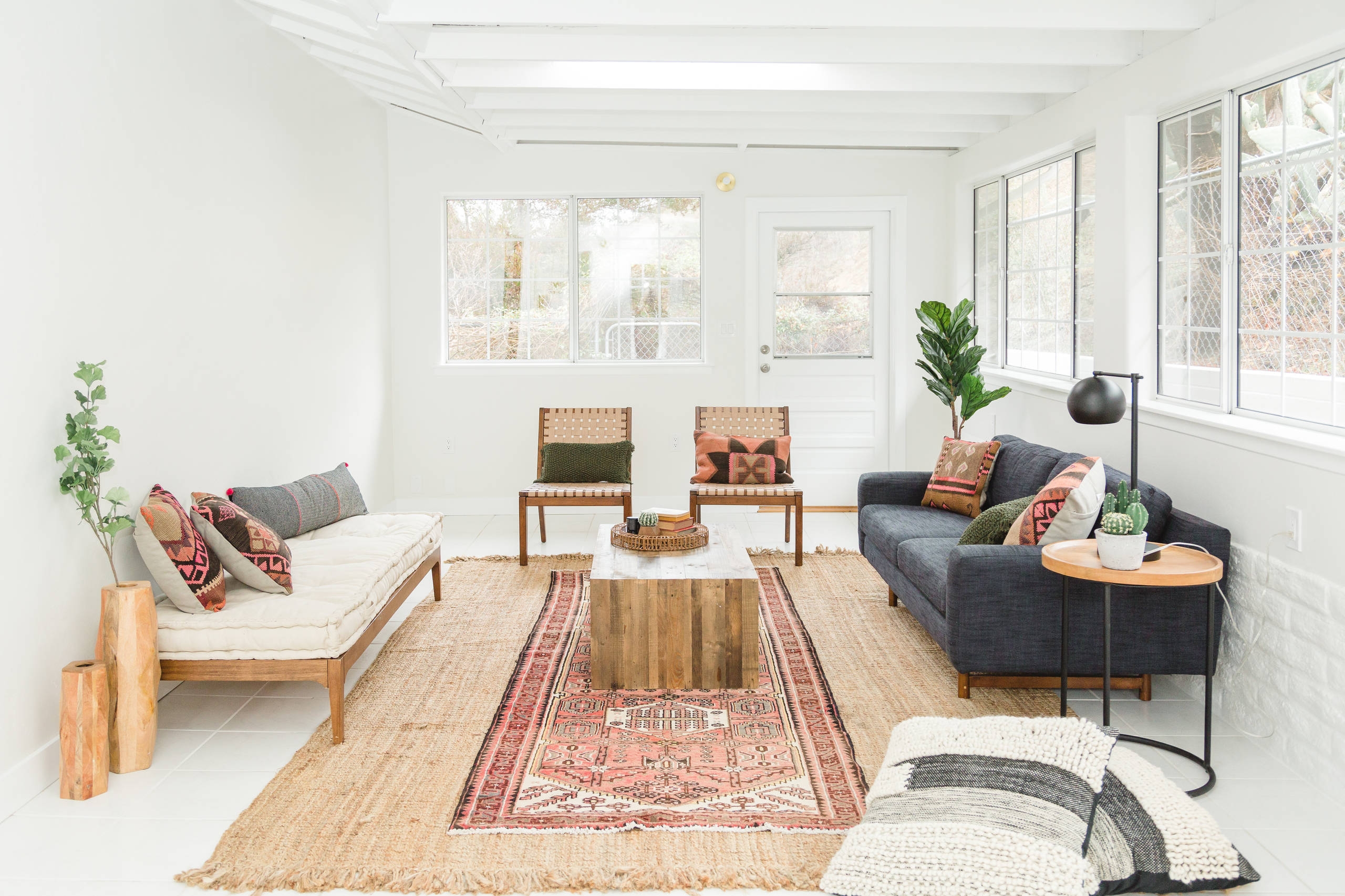 Modern converted sunroom painted white with bohemian furniture