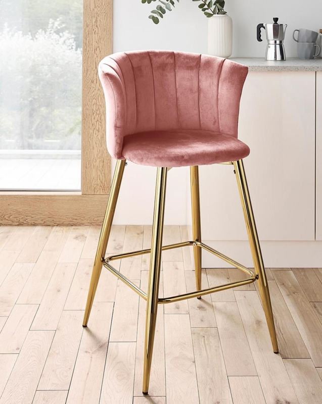 a pink velvet bar stool with gold legs in a white and wood kitchen area ...