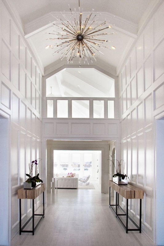 Stunning two-story foyer, white moulding on walls, wood side tables ...