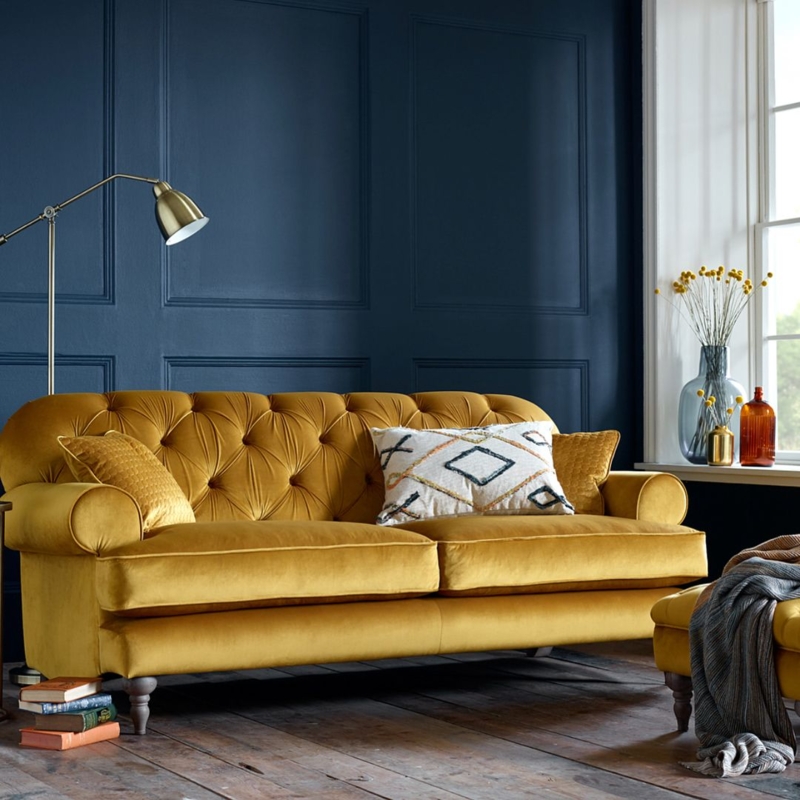Mustard Velvet Sofa Against Navy Blue Wall