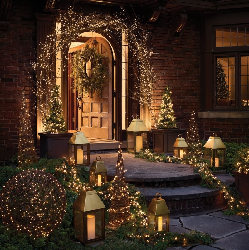 Entryway Decor: Arched fairy light canopy, brass lanterns, pine garland.