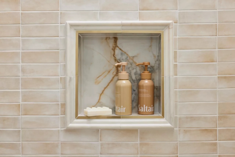 Gold Metallic Tile Trim and Marble Look Niche with Warm Beige Tiles