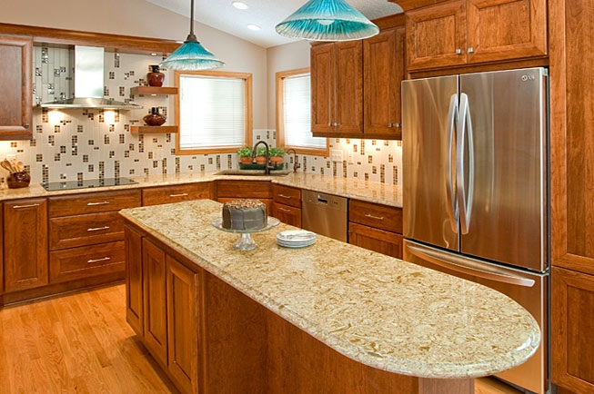 Warm Wood Cabinetry with Turquoise Pendants & Curved Granite Island