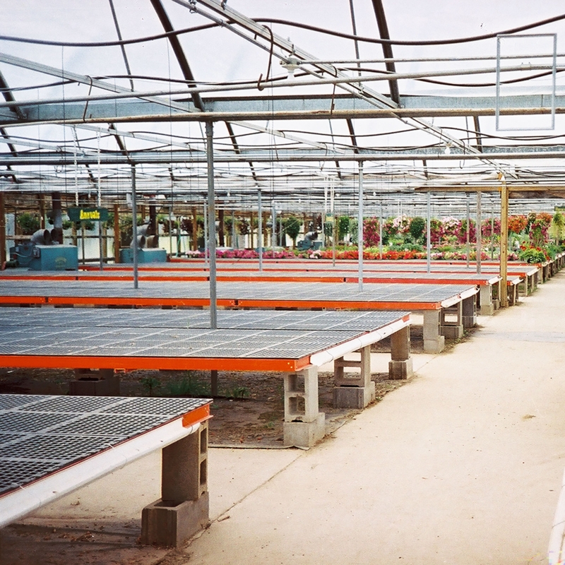Industrial Greenhouse Bench with Orange Framing on Cinder Block Supports