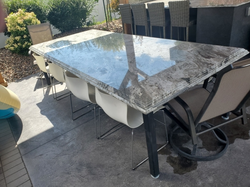 Outdoor Dining Table: Polished Granite, Tiered Edge, Black Metal Frame.