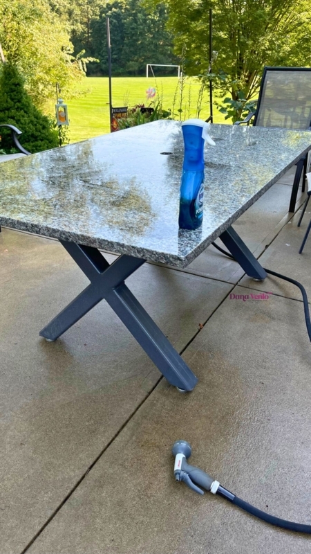 Outdoor Dining Table: Stone-Like Top, Charcoal Gray X-Frame Base, Modern.