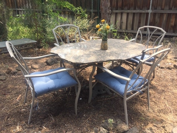 Patio Dining Set: Raw Edge Stone Oval Table, Blue Seat Cushions, Rustic.