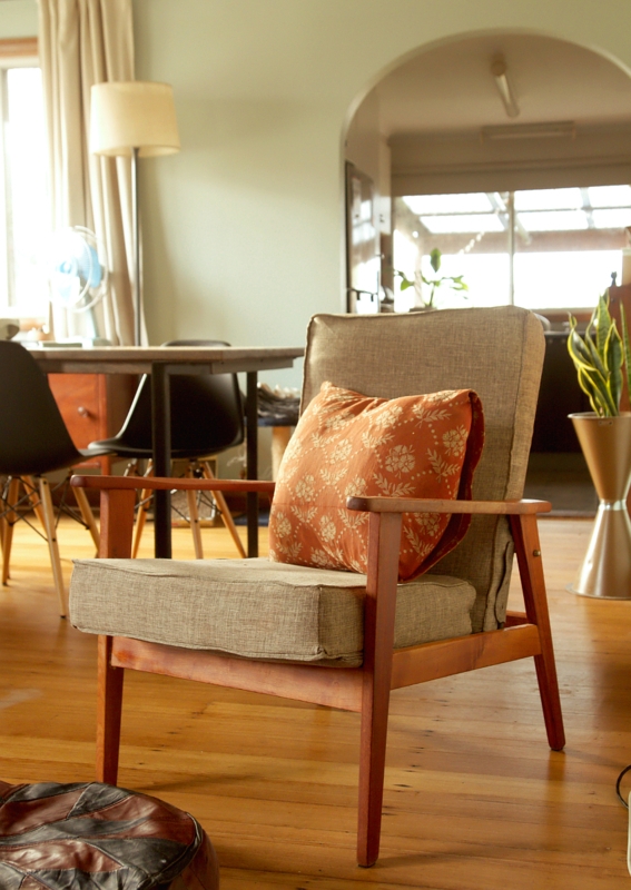 Accent Chair with Warm Wooden Frame and Patterned Botanical Pillow