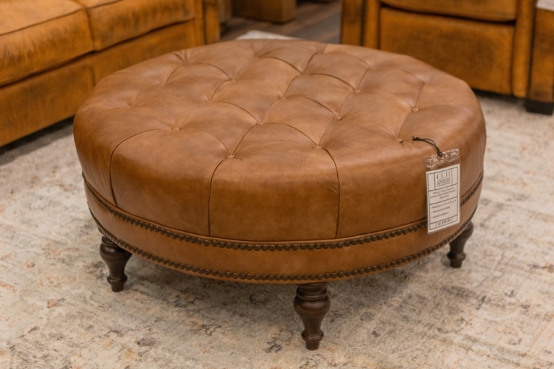 Cocktail Ottoman: Tan Leather-Like, Brass Nailheads, Turned Legs.