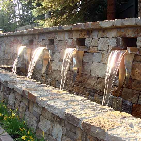 Fountain with Metallic Spouts creating Sheet Flow on Stacked Stone Wall