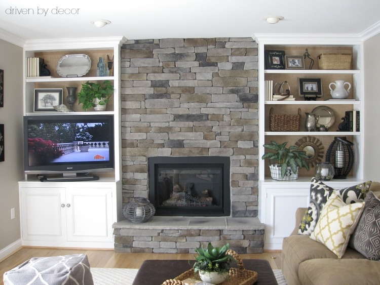 White Built-In Shelving with Textured Burlap Backing and Stone Fireplace