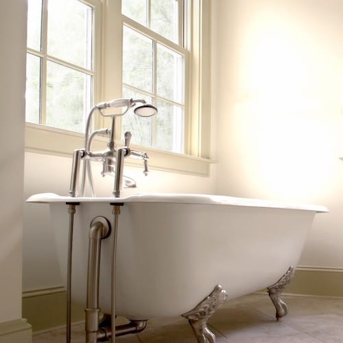 White Clawfoot Bathtub with Brushed Silver Bridge Faucet & Exposed Plumbing