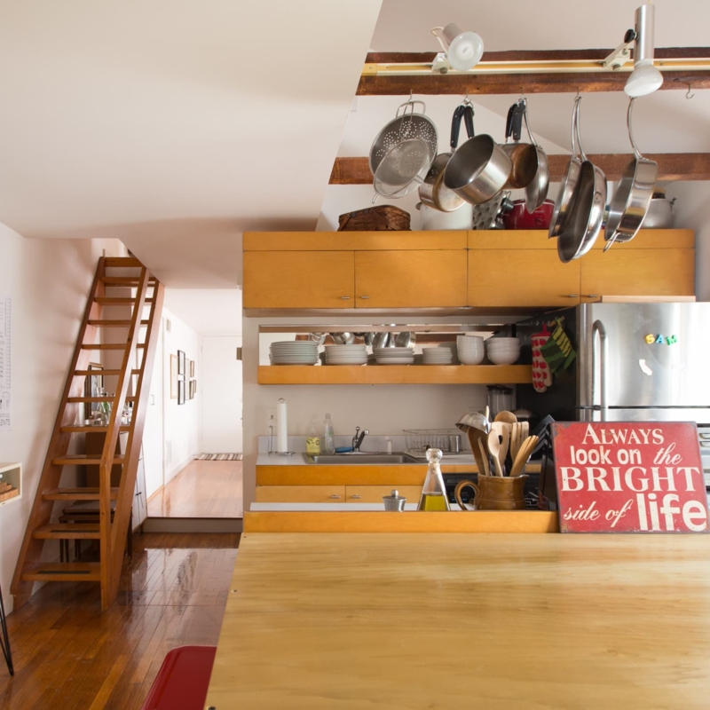 Hanging Pot Rack: Honey Wood Tones in Loft Kitchen with Ladder Access.