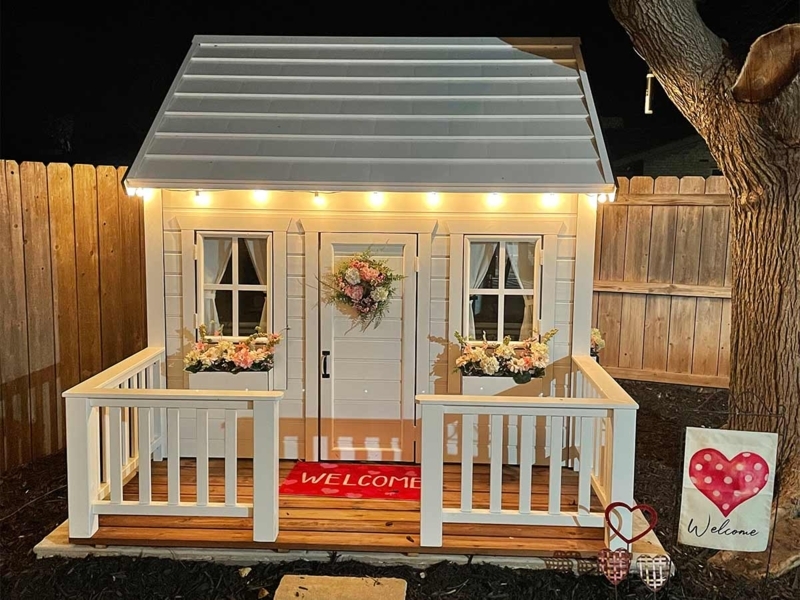 White Wooden Playhouse with Porch and Warm String Lighting