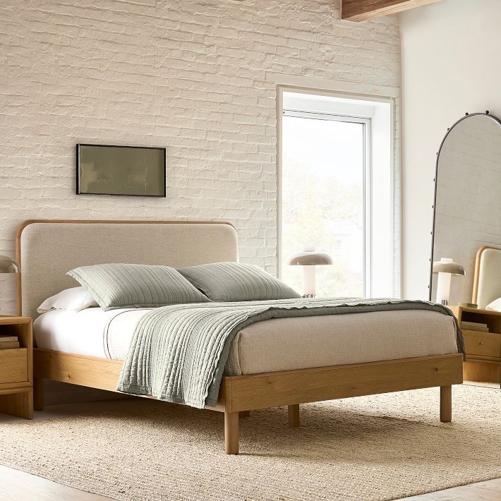 Modern Bed with Rounded Wood Frame and Neutral Upholstered Headboard.