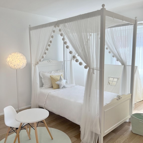 Whimsical Canopy Bed featuring Sheer Curtains and Pom-Pom Garland