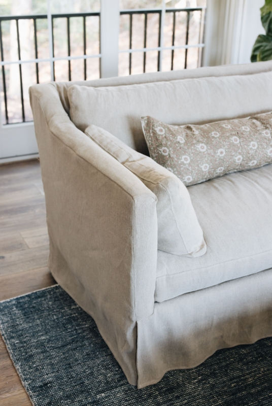 Oatmeal Slipcovered Sofa featuring Floral Bolster Pillow in Modern Farmhouse Style