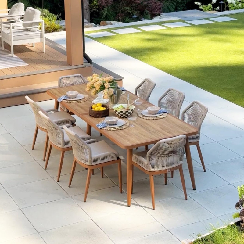 Patio Dining Set: Wicker 5-Piece with Black Metal Legs by Pool.