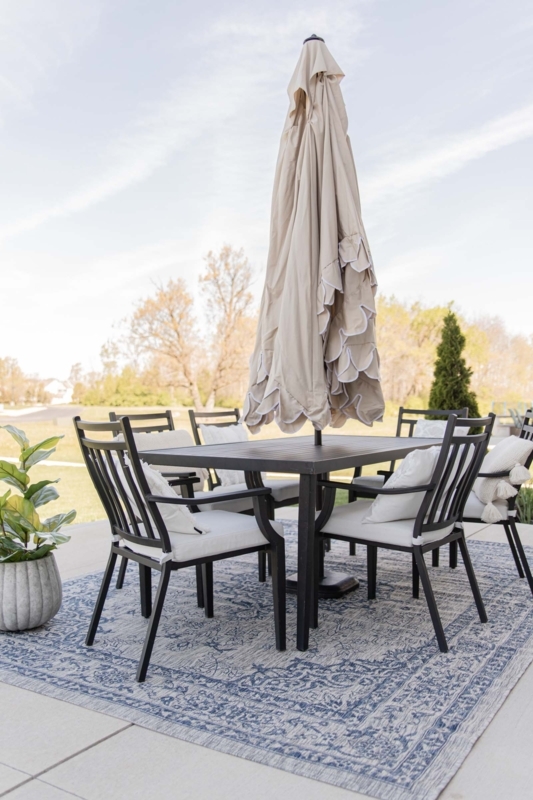 Neutral Patio Furniture Layout with Round Wood Table and Charcoal Siding
