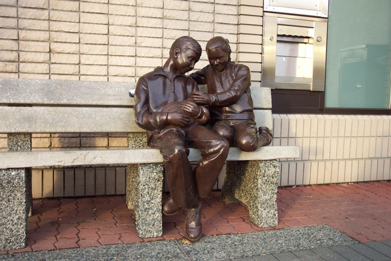 Outdoor Bench with Integrated Figurative Sculptures and Slatted Wood.