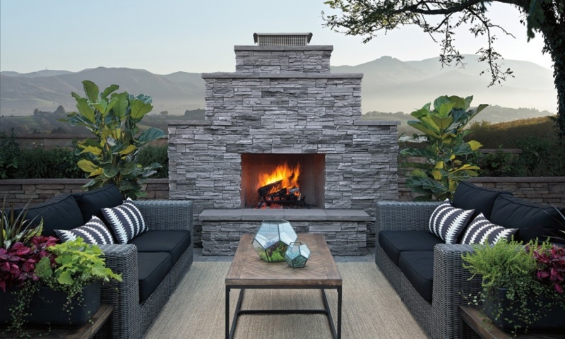 Rustic Stacked Stone Outdoor Fireplace featuring Wood Mantel and Arch