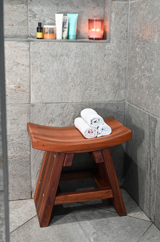 Slatted Wood Bench with Shelf Set Against Stone and Pebble Tile