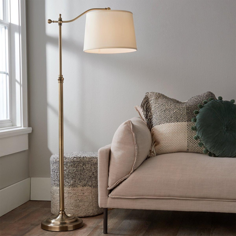 Arched Bridge Arm Floor Lamp in Aged Brass Against Blue Paneled Wall