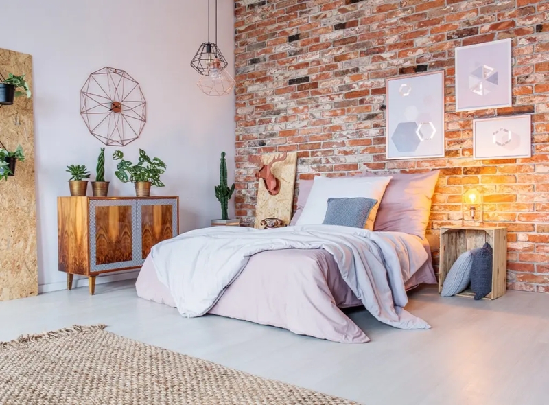 Bed with Lavender Bedding against Exposed Brick Wall & Wire Pendants