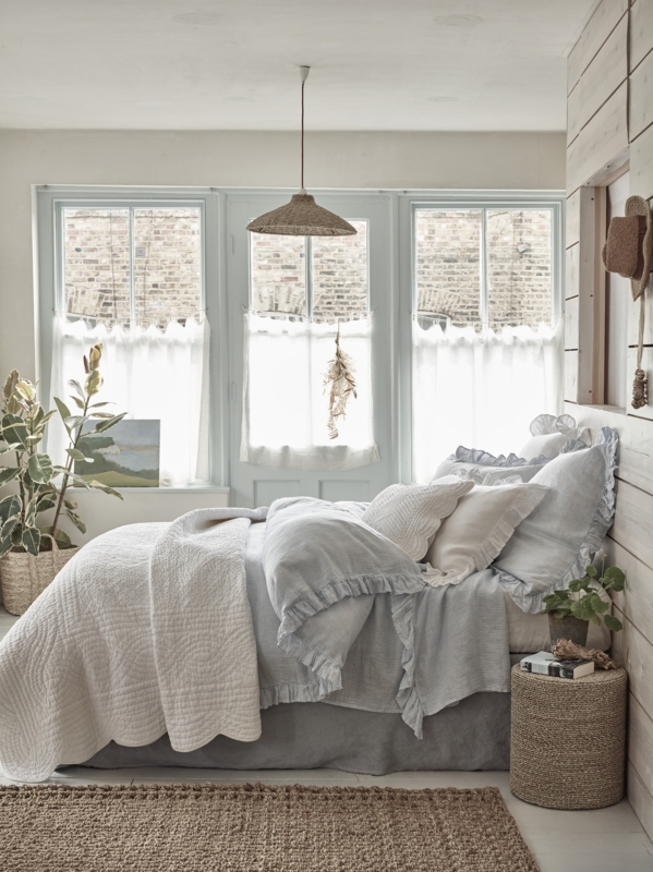 Bed with Ruffled Bedding, Quilted Throw, Woven Pendant Light