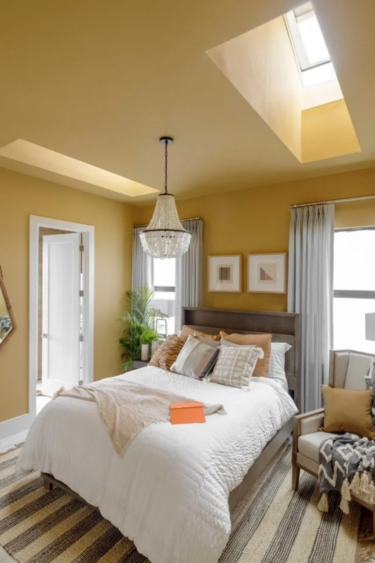 Bed with Twin Skylights and Beaded Chandelier in Mustard Yellow Room