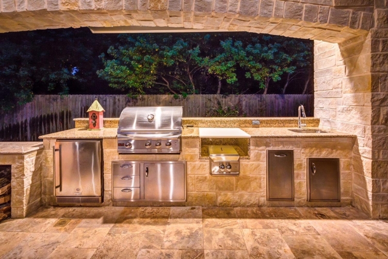 Built-In Stone Outdoor Kitchen Framed by Grand Masonry Archway