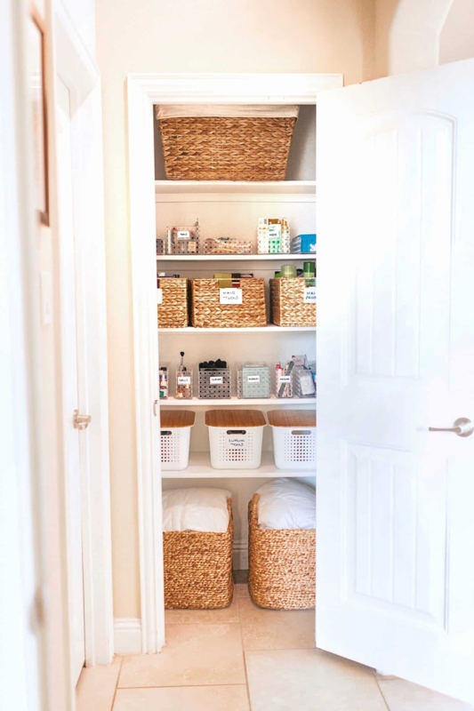 Closet Organization featuring large floor baskets and white shelving. SEO: neutral linen closet styling.