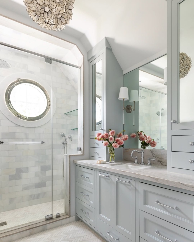 Coastal Bathroom Design Featuring Unique Porthole Window and Blue Vanities