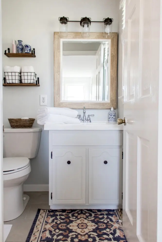 Coastal Farmhouse Bathroom with Wood Framed Mirror and Blue Rug