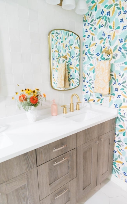 Colorful Bathroom featuring vibrant floral wallpaper and gold fixtures.