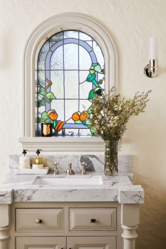 Cream Vanity with Marble Countertop under Arched Stained Glass Window
