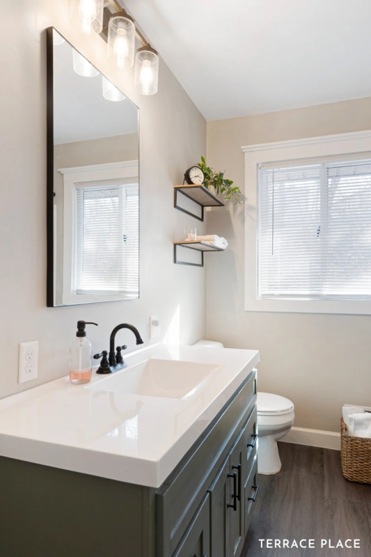 Dark Green Bathroom Vanity with Integrated White Sink and Black Hardware