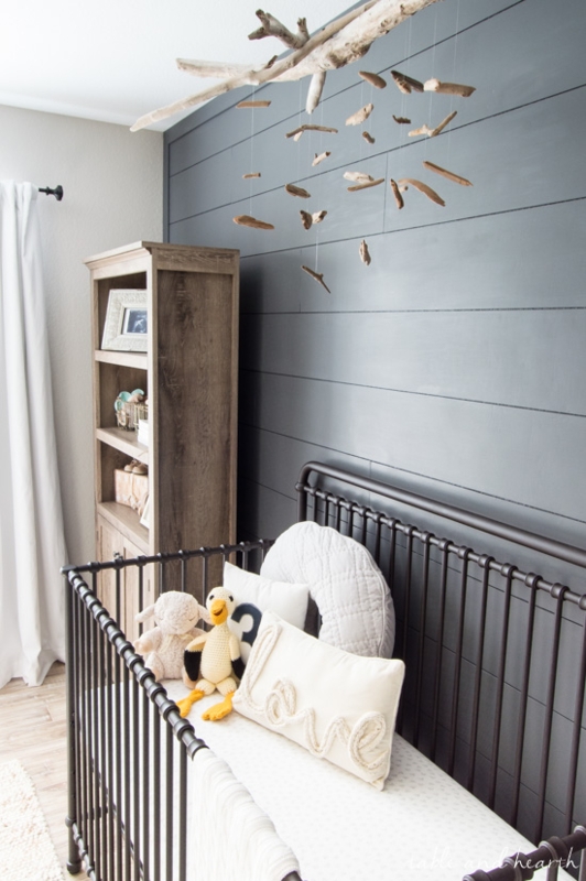 Dark Metal Crib Against Charcoal Shiplap Wall in Coastal Nursery