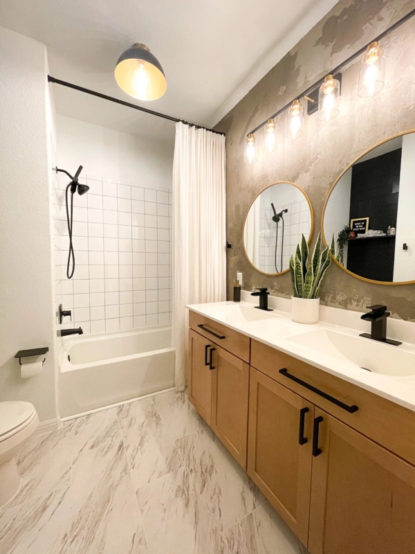 Double Vanity with Textured Accent Wall and Round Gold Mirrors