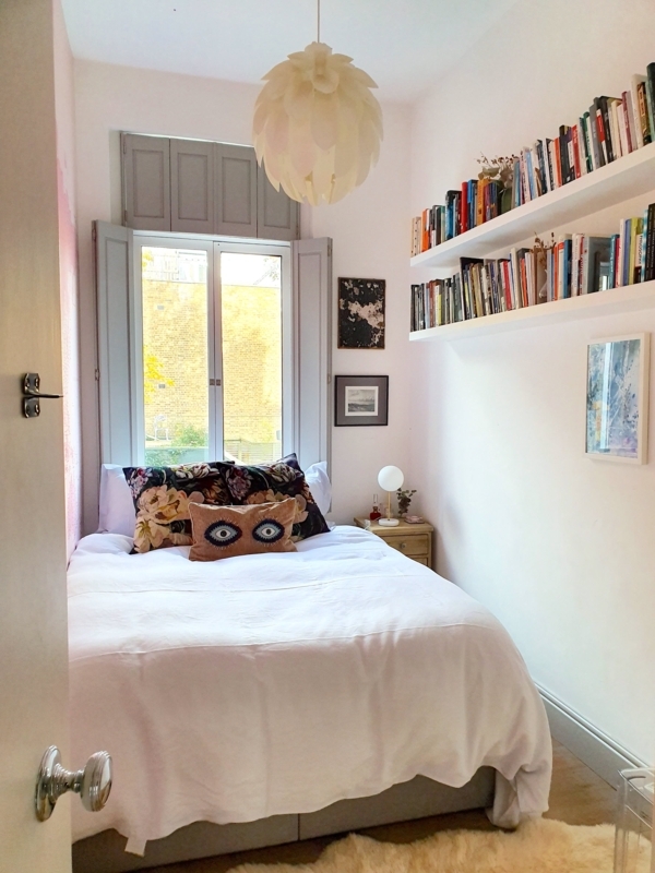Eclectic Bedroom With Wall-To-Wall Floating Bookshelf and Shutters