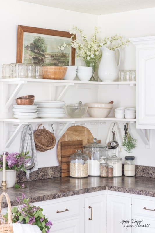European Farmhouse Kitchen with L-Shaped Shelving and Pastoral Art
