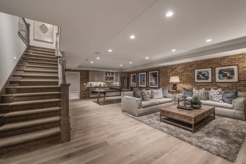 Exposed Brick Wall Basement Design with Kitchenette and Gray Sofas