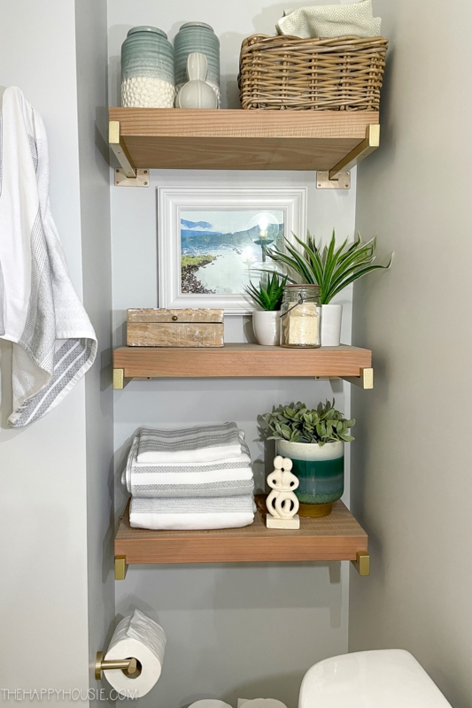 Floating Shelves with gold brackets over toilet. SEO: organic modern bathroom shelving ideas.