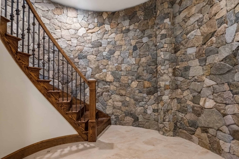 Foyer Design with Curved Staircase and Mosaic Fieldstone Accent Wall