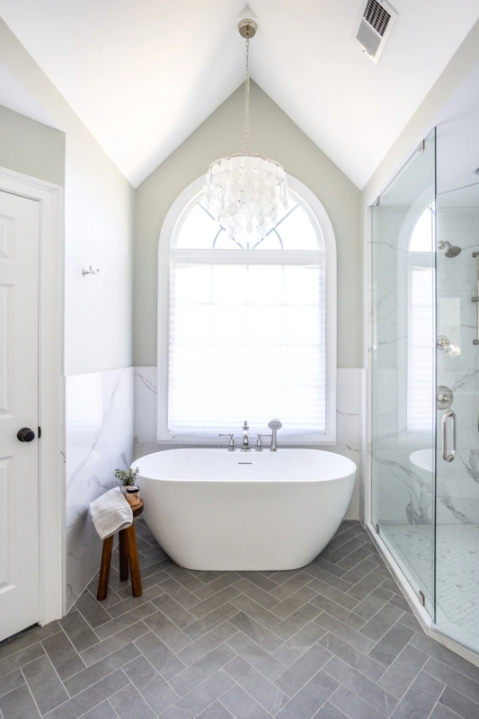 Freestanding Tub Under Arched Window with Herringbone Floor