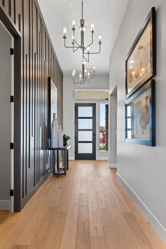 Hallway featuring Vertical Slat Wall Design and Tiered Chandeliers