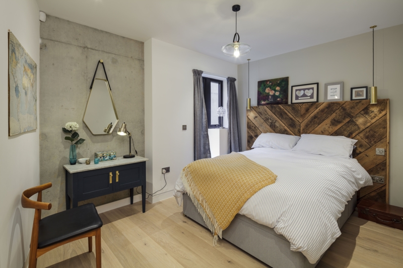 Industrial Basement Bedroom with Concrete Accent Wall and Navy Vanity