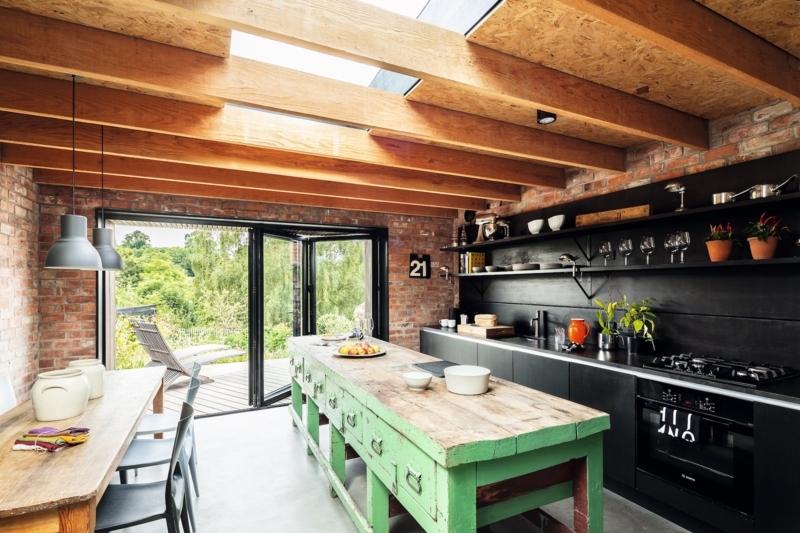 Industrial Kitchen with Skylight Ceiling Beams and Green Distressed Island